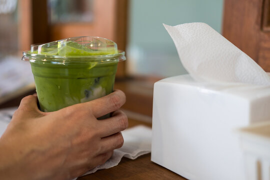 Close up hand pick up a glass of iced matcha latte