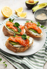 Preparing avocado salmon toasts with sesame seeds and lemon