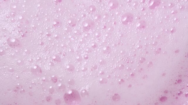 Slow motion close-up soap foam texture on pink background, white shampoo soapsud