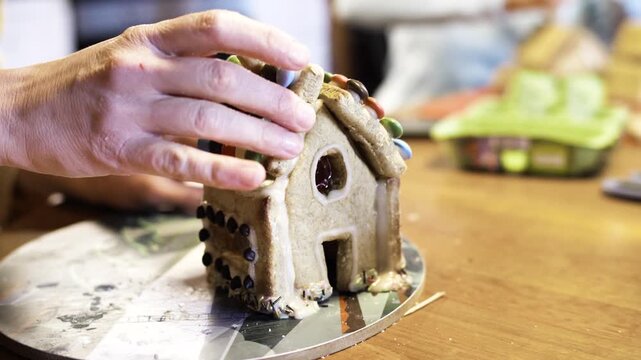 D&eacute;coration de maison en pain d&rsquo;&eacute;pices avec des bonbons mains f&eacute;minines en cuisine. High quality 4k footage