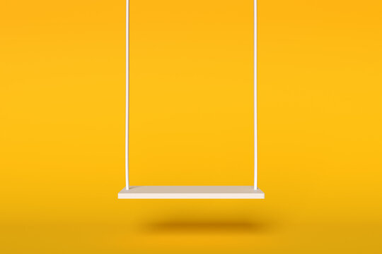 Empty swing on yellow background representing childhood fun