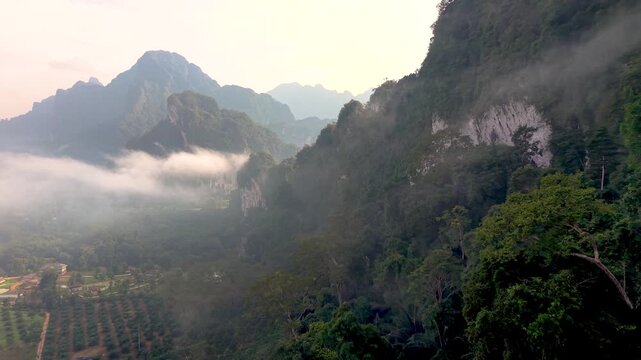 Discover the enchanting beauty of Khao Sok National Park as morning mist rises over the majestic mountains. Lush greenery and tranquil vibes create a serene atmosphere in this stunning location.