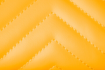 Fototapeta premium Detailed view of vibrant yellow quilted leather texture with diagonal stitching pattern close up