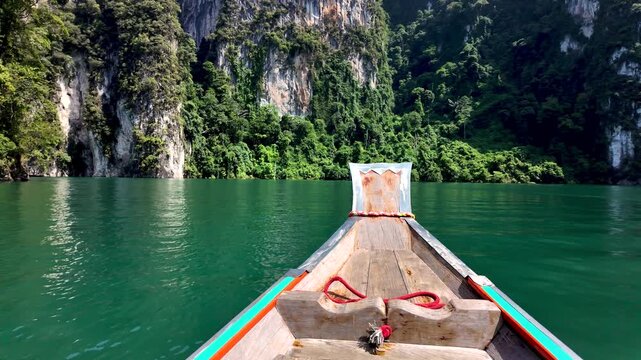 Glide across the emerald waters of Khao Sok Thailand in a longtail boat.