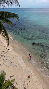 Walk along the soft sandy shores of Koh Kood Island, Thailand, surrounded by swaying palm trees and tranquil turquoise waters. Experience the beauty and peace of this tropical paradise.