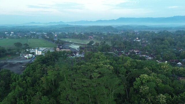Aerial Morning View of Passing Trains Along Rural Railway with Rice Fields and Mount Merapi - Merbabu Background, Yogyakarta, Indonesia