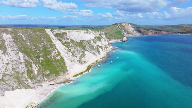 Ascending aerial shot travelling over Mupe Bay and chalk cliffs and along the Jurassic Coastline of Dorset