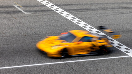 Fototapeta premium Motion blur, Race car racing on speed track, race car on road crossing start and finish line, Target business achieve and victory concept.