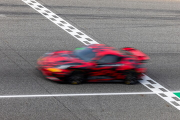 Fototapeta premium Motion blur, Race car racing on speed track, race car on road crossing start and finish line, Target business achieve and victory concept.
