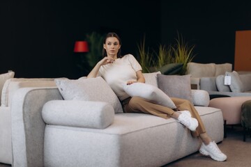 Obraz premium Young woman relaxing on comfortable modern sofa in furniture showroom