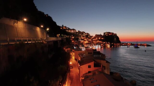 Night aerial view of Chianalea Scilla with glowing village lights and coastline
