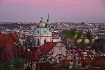 Fototapeta premium Church of Saint Nicholas, Prague cityscape at sunset, Czech Republic. View from above stock photo images. Prague Castle area towards Mala Strana photo. Prague old town early evening