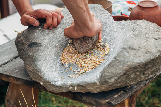 Human hand rotating an ancient stone grinding machine for smashing grains. Handmade manual equipment grind mill