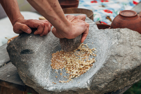 Human hand rotating an ancient stone grinding machine for smashing grains. Handmade manual equipment grind mill