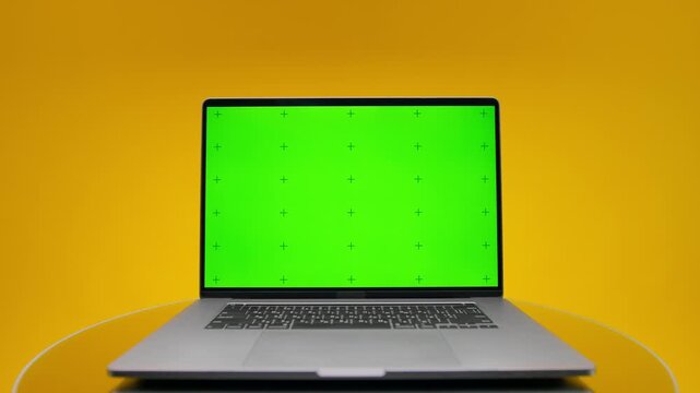 Laptop mockup with green screen display on yellow background