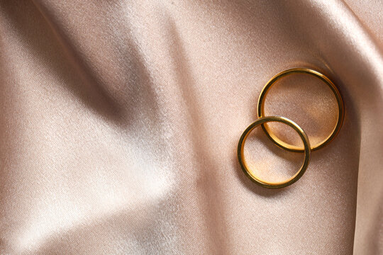 Wedding rings on beige cloth as background