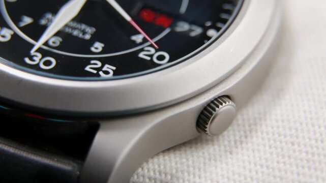 Macro close up of an automatic mechanical field watch with moving arms
