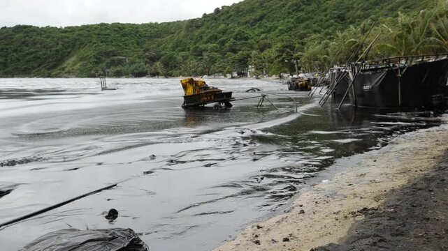 Petroleum spill mixed with other chemical substances on sea and sand surface. Pollution footages, Samet Island, Thailand.
