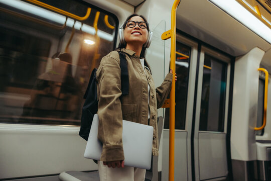 Commuter woman on train smiling with laptop