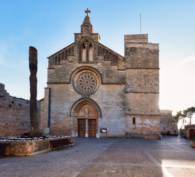 Medieval parish church Sant Jaume with battlements and palm trees at street corner in Alcudia, Mallorca, Spain