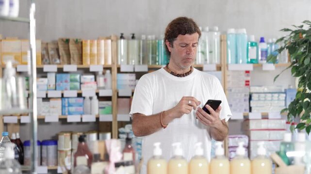 European holds a mobile phone in his hands and scrolls through the online website of a pharmacy and checking information about goods before buying.