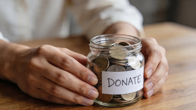 Donation jar with coins in hands, charity and fundraising concept, giving support, nonprofit help, community care and financial contribution