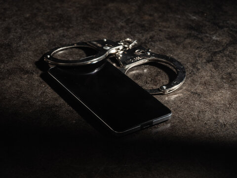 Mobile phone evidence and police handcuffs on desk