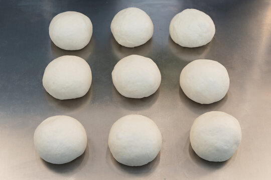 Top view of fresh raw dough balls on a silver metal tray for artisan bread baking.