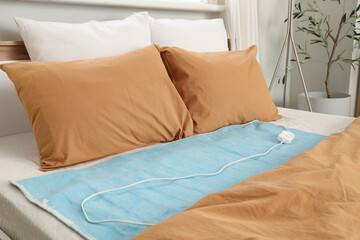Electric heating pad on bed in room © Pixel-Shot