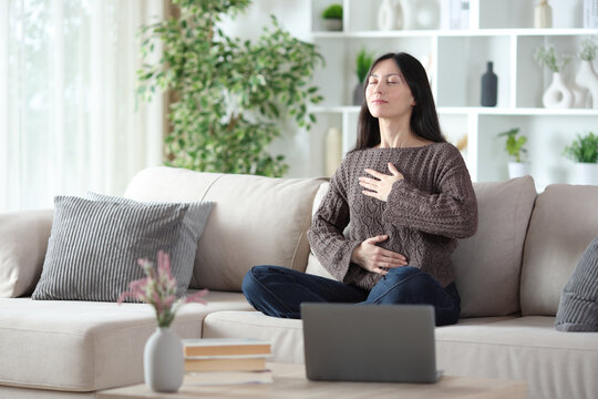 Asian woman doing online guided breathing exercises