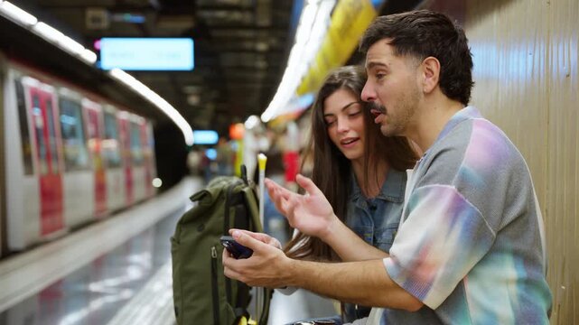 Couple planning travel route using phone in metro station