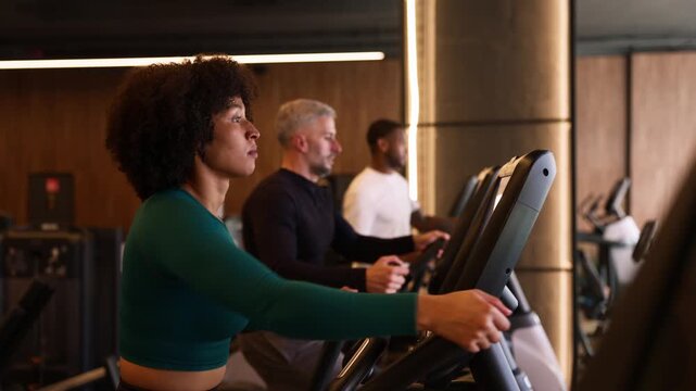 Determined woman leading cardio workout session on elliptical trainers