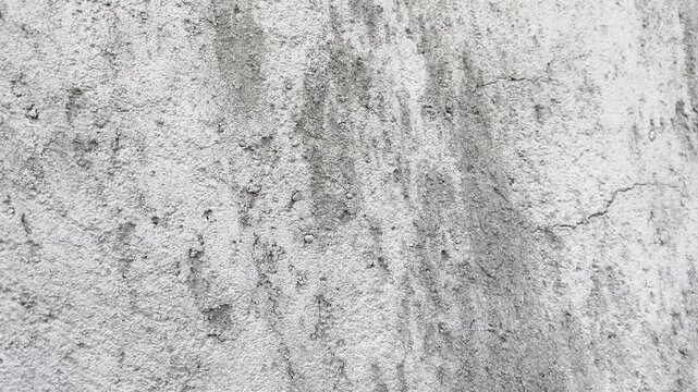 Rough weathered concrete wall with dark stains