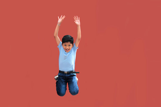9-year-old Latino boy with dark skin jumps for joy to celebrate his excitement