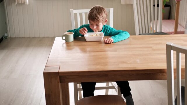 6 years old boy eats instant noodle from box. Child is eating Asian ramen. Lunch time. A good appetite. Tasty children food. Close-up portrait. Carbs dinner. Fast food. Kid eating by himself with fork