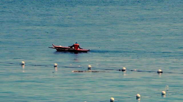 A fisherman watches over a laid-out fishing net while angling on Hilutungaan Channel in Lapulapu City, Philippines. This body of water is located between Mactan Island and Olango Island.