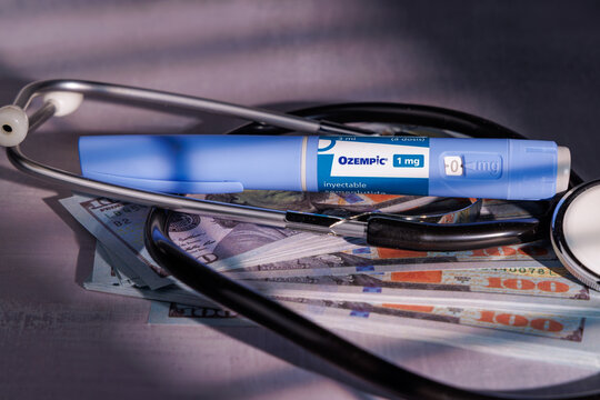 Medical Ozempic glp-1 injectors with stethoscope over cash on a cement surface for illustrating the price of diabetes treatment. In Barcelona - Spain; March 22, 2026.