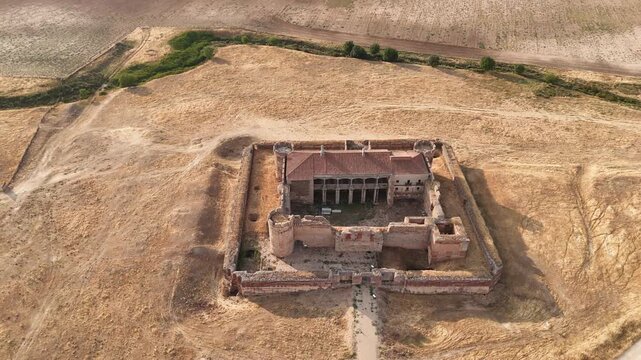 Drone orbiting and pulling away from abandoned castle in rural countryside