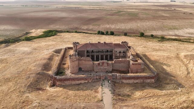 Front drone shot pulling back and rising away from abandoned castle
