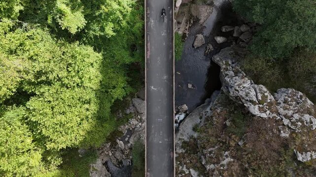 Top down drone view of bridge with two gravel cyclist crossing river