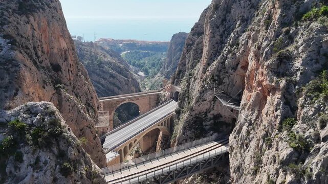 Descending drone shot revealing Mascarat Canyon bridges and road traffic