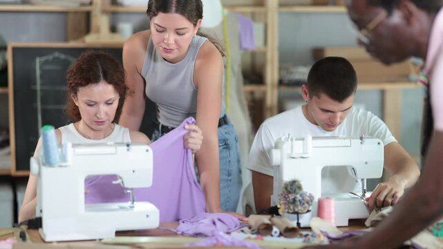 Experienced seamstress mentoring fashion students in garment construction class 