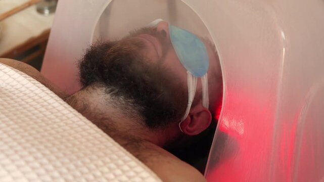 Bearded Man with Blue Eye Patches Lying Inside Japanese Head Spa Bowl with Purple UV LED Illumination, Luxury Scalp Steaming and Chromotherapy Ritual in Premium Beauty Salon, Male Wellness Treatment 