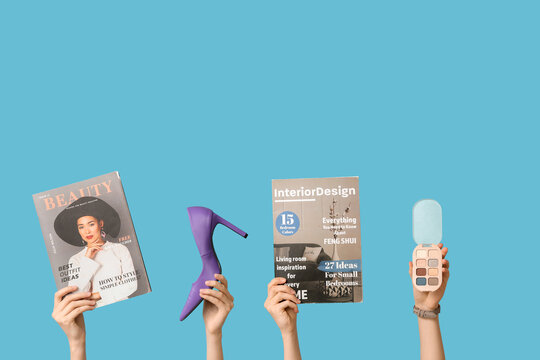 Female hands with different magazines, high heel and palette of eyeshadows on blue background