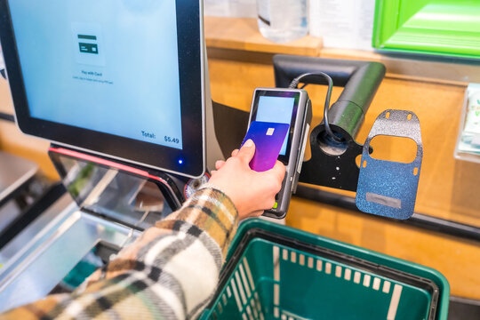 Person making contactless payment at grocery store self checkout