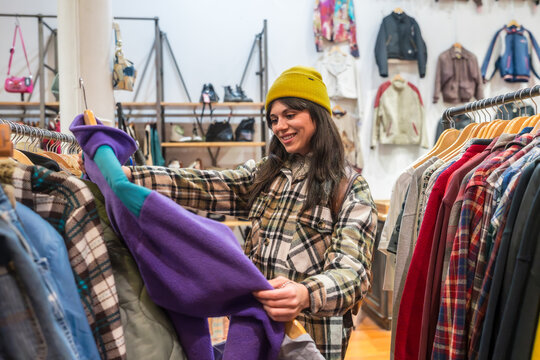 Young woman finding vintage clothes in a thrift store