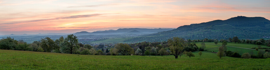Fototapeta premium Wide panorama of Burg Teck and the Swabian Alb ridge at sunrise in spring, seen from Käppele. Dettingen unter Teck, Baden-Württemberg, Germany.