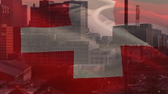 Gentle breeze starting, large red flag with white cross waving and revealing skyline lights