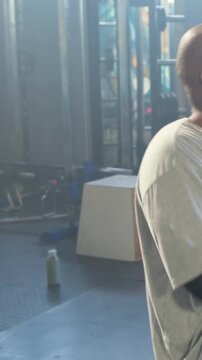 Vertical video: Picking up medball, man in red-shorts doing core twists on bench in gym, copy space