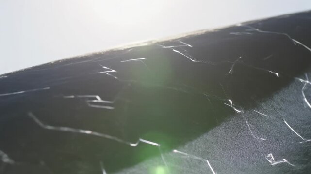 Panning camera highlighting matte black panel texture in studio, showing scratches and green flare